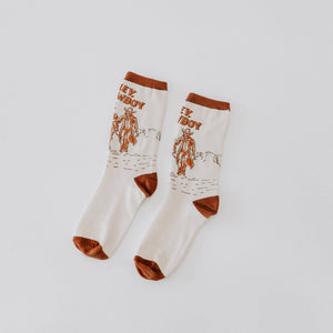Pair of socks with cowboy graphics and text on a light gray background