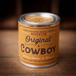 Canister of 'Original Cowboy' candle on a wooden surface