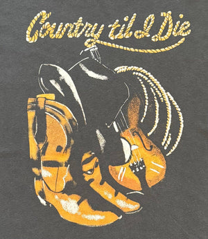 T-shirt design with cowboy boots, guitar, and 'Country til I Die' text on a dark background.