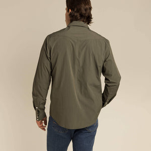 Person wearing a green shirt and blue jeans on a beige background