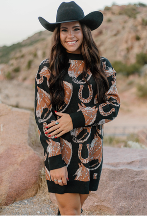 Woman wearing a patterned dress and black cowboy hat outdoors.