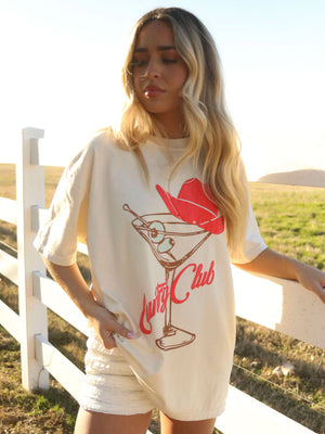 Woman wearing a 'Café Club' t-shirt with a martini glass design outdoors.