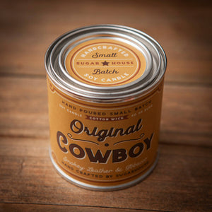 Candle can labeled 'Original Cowboy' on a wooden surface