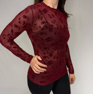 Red long-sleeve top with black pattern worn by a person on a plain background