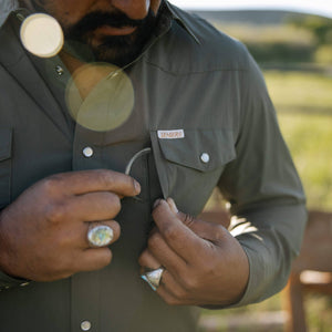 Man wearing a green jacket with a brand logo, outdoors.