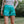 Person wearing a floral top and teal fringed shorts in a natural setting