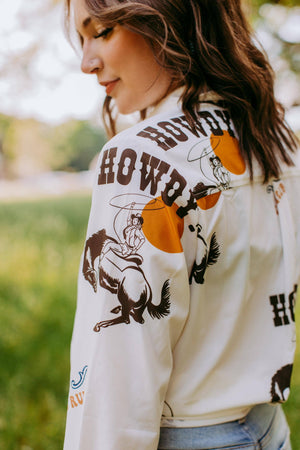 Person wearing a white jacket with cowboy graphics outdoors