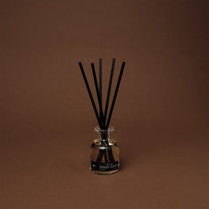 Clear diffuser bottle with black sticks on a brown background