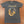 Gray t-shirt with a graphic of cowboy boots, guitar, and text 'Country til I Die' on a brown surface.