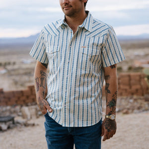 Man wearing a patterned shirt standing in a desert landscape