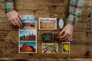 Person arranging scenic postcards on a wooden surface