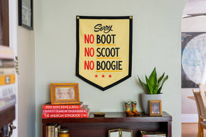 A rectangular camp flag with a cream body and the text 'Sorry NO BOOT NO SCOOT NO BOOGIE' printed in red, black, and gold colors.