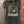 Black t-shirt with eagle graphic and 'Desperado' text hanging against a rusty metal background