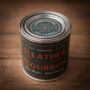 Candle canister labeled 'Leather & Bourbon' on a wooden surface