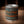 Candle in a can labeled 'Leather & Bourbon' on a wooden surface