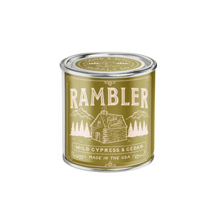 Rambler candle tin with green label and cabin illustration on a white background