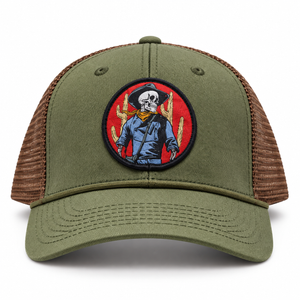 An olive green trucker cap with brown mesh side panels and a circular embroidered patch on the front featuring a cowboy skeleton on a red background.