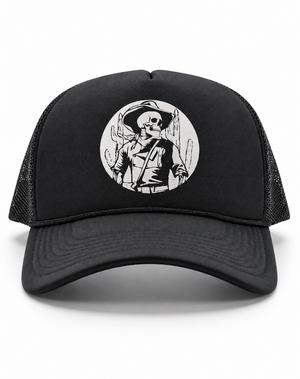 A black trucker hat with a curved brim, black mesh back panels, and a circular black-and-white graphic on the front featuring a cowboy skull illustration.