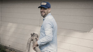 Male model wearing Ranger cap carrying wood log.