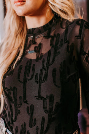 Person wearing a black see-through mesh shirt with cactus pattern