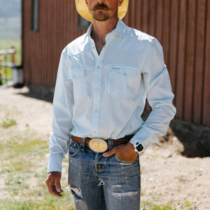 Man wearing a white shirt, blue jeans, and a yellow hat outdoors.