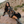 Woman in a patterned dress and cowboy boots sitting on a rock with a mountainous background