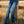 Person wearing blue jeans standing next to a wooden fence in a field.