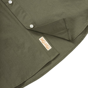 Close-up of a green shirt with a brand label on a white background