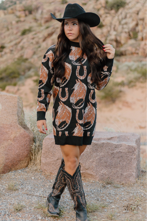 Woman wearing a patterned dress and cowboy boots in a desert setting